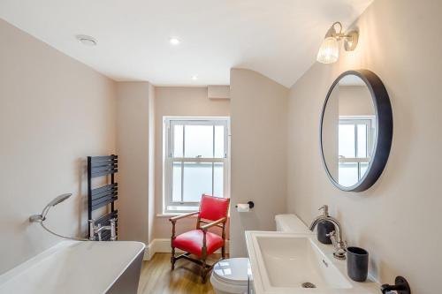 a bathroom with a sink and a mirror and a red chair at 2 Bed in Pakefield oc-p32922 in Lowestoft