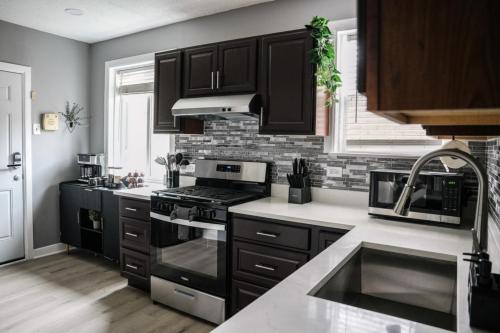 a kitchen with black cabinets and a stove top oven at 2BR w/ Workspace - Coffee Bar - Near Transit in Chicago