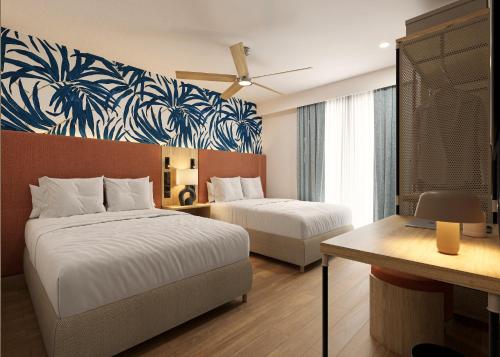 a hotel room with two beds and a desk at voco Surfside Aruba by IHG in Oranjestad