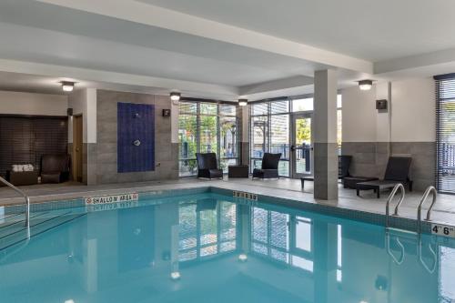 a swimming pool in a hotel with chairs and tables at Homewood Suites by Hilton Toronto-Ajax in Ajax