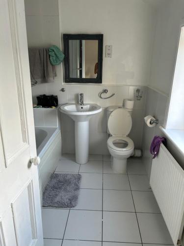 um banheiro com vaso sanitário, pia e espelho em Cozy & Comfy Apartments Dundee em Dundee