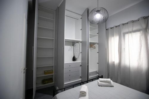 a white closet with white shelves and a window at Perivola apartment in Patra