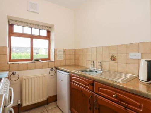 een kleine keuken met een wastafel en een raam bij Ticklepenny in Cornisholme