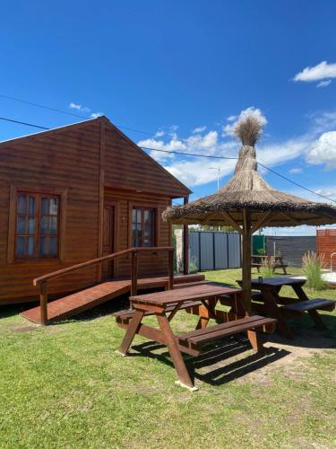 una cabina di legno con un tavolo da picnic e un ombrellone di paglia di Cabaña Isi Cdelu a Concepción del Uruguay