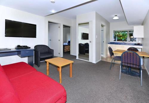 a living room with a red couch and a table at Anika Motel in Christchurch