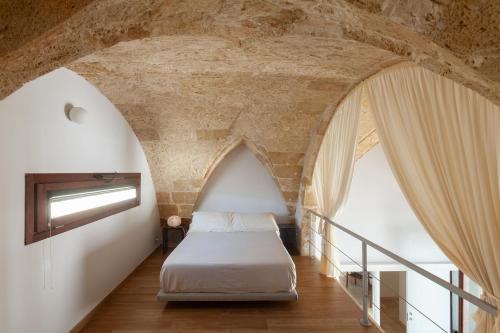 a bed in a room with a stone wall at Monteforte Suite & Spa in Ugento