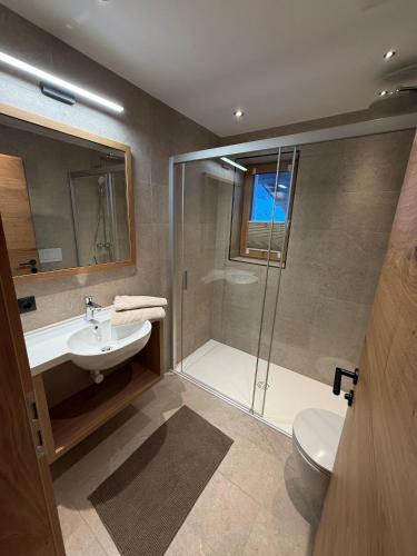 a bathroom with a shower and a sink and a toilet at Pension Kristall in Flirsch