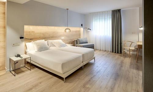 um quarto com uma grande cama branca e uma cadeira em La Retama Houstime em Ayacucho