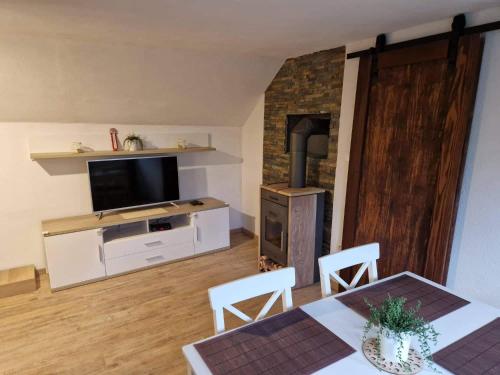 Una sala de estar con televisión, mesa y sillas. en Koča na Pikovem, en Črna na Koroškem