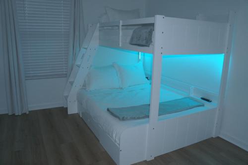 Townhome near beach and The Wharf Amphitheater! في شاطئ أورانج: غرفة نوم بسرير بطابقين أبيض مع أضواء زرقاء