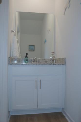 Townhome near beach and The Wharf Amphitheater! في شاطئ أورانج: طاولة حمام مع حوض ومرآة