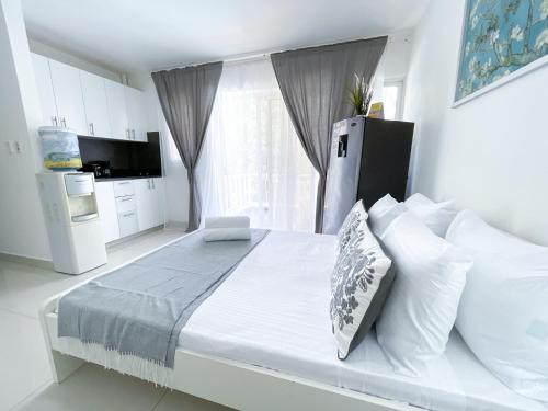 um quarto branco com uma grande cama branca com travesseiros em RELAX STUDIOS Tropicana Sol Caribes SUITES - Beach Club, Spa, Restaurants - playa Los Corales em Punta Cana
