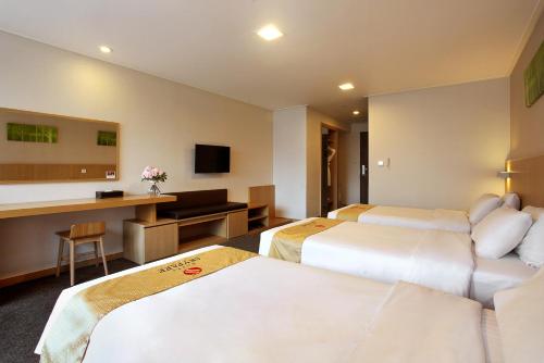 a hotel room with two beds and a desk at Hotel Skypark Jeju 1 in Jeju