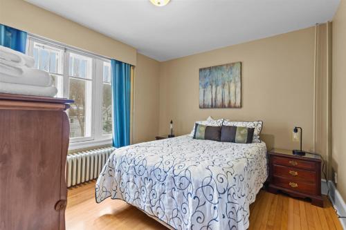 een slaapkamer met een bed, een dressoir en 2 ramen bij Midstream Loft 2BR Parking W&D in St. John's