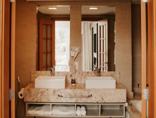 a bathroom with two sinks and a large mirror at Hotel Amantykir in Itajubá