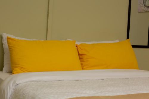 IJ Apartments في ندولا: سرير مع وسادتين صفراوتين فوقه