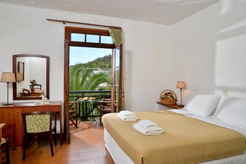 a bedroom with a bed and a desk and a window at Vagia Traditional, Aegina Island in Vaia