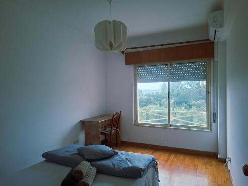 Un dormitorio con una cama y una ventana y un escritorio. en Deluxe Room Santarém, en Santarém