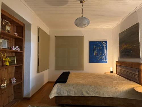 1 dormitorio con 1 cama y una pintura azul en la pared en MZ Maison de la Place, en Eptalofos