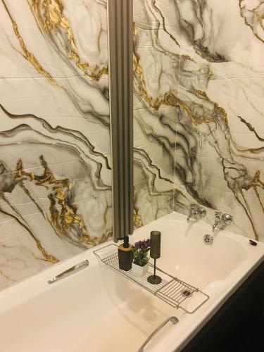a bathroom with a white tub with a marble wall at Panaroma View in Graskop