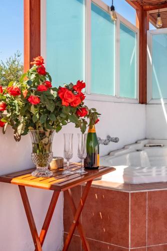 a table with two glasses and a vase with red flowers at Private Pool & Jacuzzi Family House, Teques in Tlatenchu