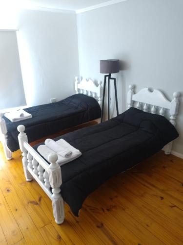 due letti in una stanza con pavimenti in legno di JAS departamento a General Acha