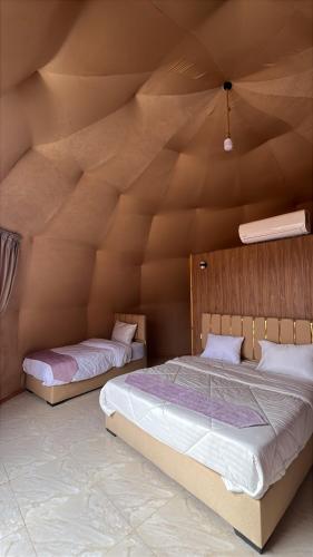 two beds in a room with a wooden ceiling at Wadi Rum Star Haven camp in Wadi Rum