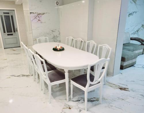 A&G SoDYBA LIUXAPARTAMENT في بلونج: طاولة طعام بيضاء وكراسي عليها شماعات
