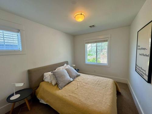 a bedroom with a bed and a table and two windows at Honeysuckle Beach Oasis at Veranda Beach in Oroville