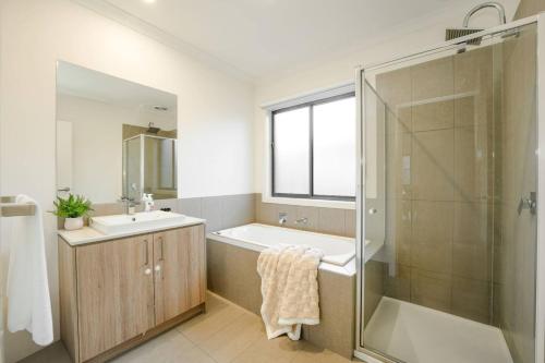 Melton SouthにあるOpen Plan Comfort Sunny Living BBQ in Backyardの浴槽、洗面台、シャワーを備えたバスルーム