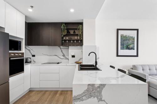 a white kitchen with a sink and a counter at Stylish 2BR Retreat in Heart of Darling Harbour! in Sydney