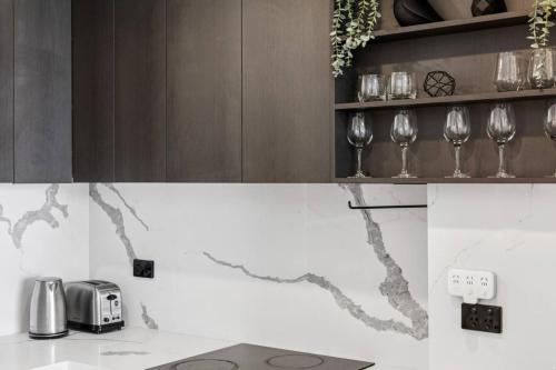 a kitchen counter with wine glasses on a shelf at Stylish 2BR Retreat in Heart of Darling Harbour! in Sydney