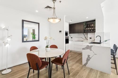 a kitchen and dining room with a white table and chairs at Stylish 2BR Retreat in Heart of Darling Harbour! in Sydney