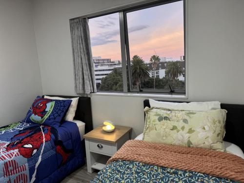 a bedroom with a bed and a window with a view at Charming & Cozy Apartment in the Heart of Auckland - 2 bd-2 bth-free carpark in Auckland
