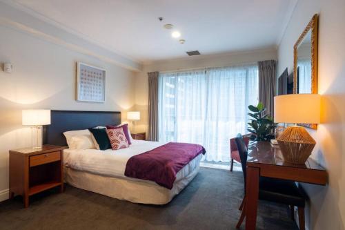 a hotel room with a bed and a desk and a window at Chic Hotel Room at City Life Auckland in Auckland