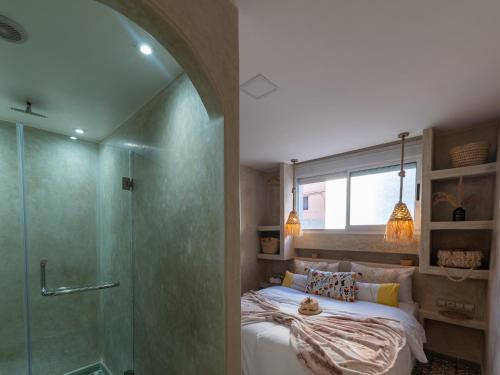 a bedroom with a bed and a glass shower at Waves Hunter Surf House in Agadir