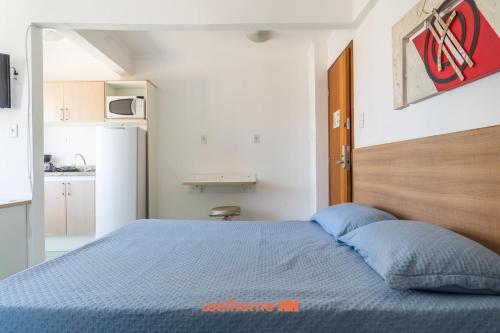a bedroom with a blue bed and a kitchen at Apartamento em Macae no Centro da Cidade in Imbetiba