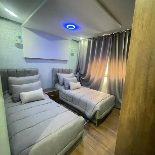 a bedroom with two beds and a blue light at Prime stay downtown Meknes in Meknès