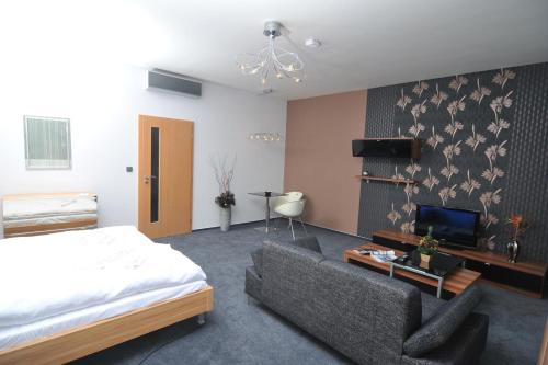 - une chambre avec un lit, un canapé et une télévision dans l'établissement Pension Milk Inn, à Prague