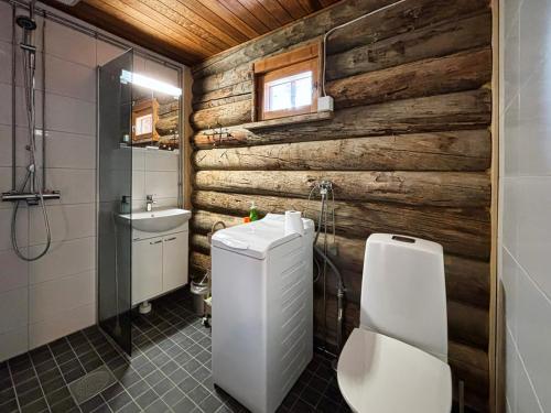 baño con aseo y pared de madera en Ski-inn kelohuoneisto Pyhätunturissa, en Pelkosenniemi