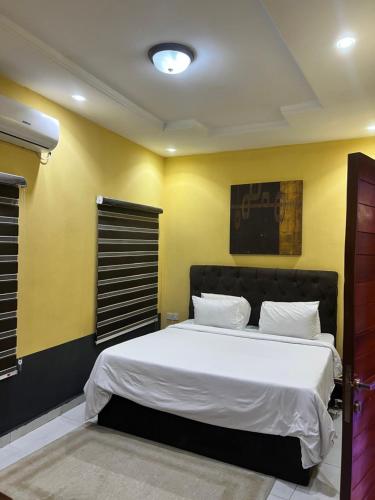 Un dormitorio con una gran cama blanca con paredes amarillas. en The Private Pearl Apartment, en Ikeja