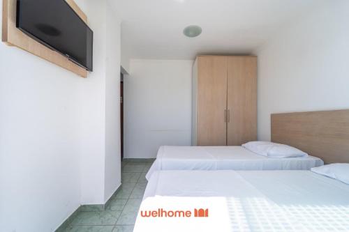 twee bedden in een kamer met een tv aan de muur bij Apartamento em Macae Proximo a Praia do Farol in Imbetiba