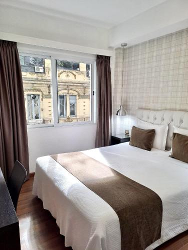 ein Schlafzimmer mit einem großen Bett und einem großen Fenster in der Unterkunft Hotel Alvear in Montevideo