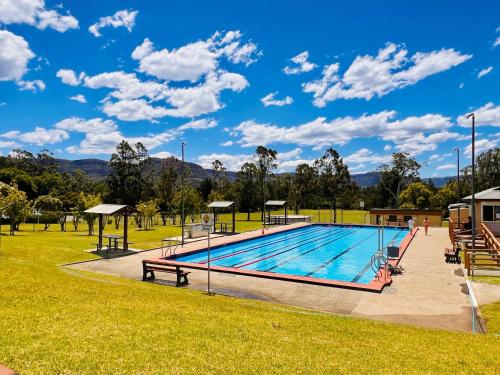 a swimming pool in a park with a blue sky at The Tailor's Cottage Kangaroo Valley in Kangaroo Valley