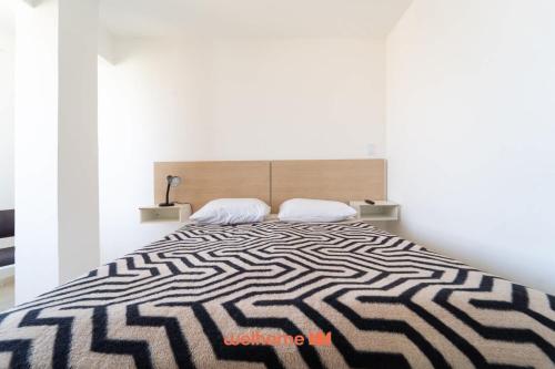 ein Schlafzimmer mit einem großen Bett mit einer schwarzen und weißen Bettdecke in der Unterkunft Apto no Centro de Macae a 550m da Praia do Farol in Imbetiba