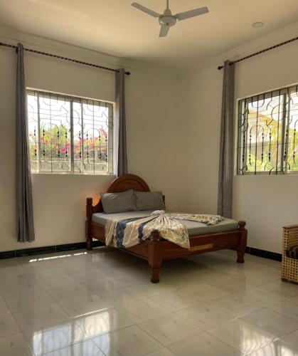 a bedroom with a bed and two windows at Kijani House in Banda Kuu