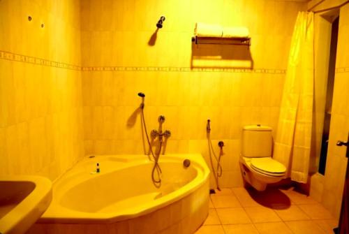 a bathroom with a tub and a toilet and a sink at Boho Heritage in Kochi in Cochin