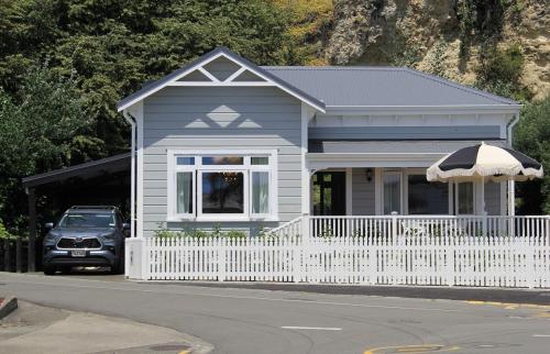 a small house with a white fence and a car at Seapoint Cottage, Luxury Accommodation in Napier