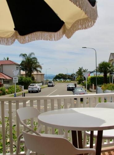 a table and chairs on a balcony with a street at Seapoint Cottage, Luxury Accommodation in Napier