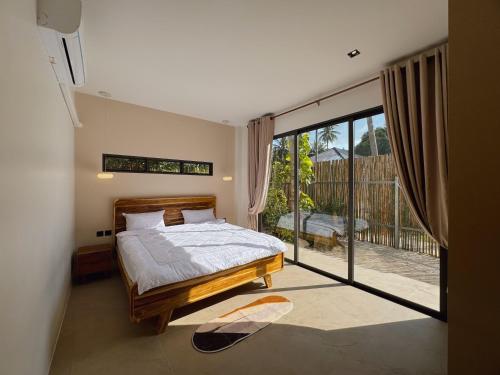 - une chambre avec un lit et une grande porte coulissante en verre dans l'établissement Beach front villa, à Mae Haad